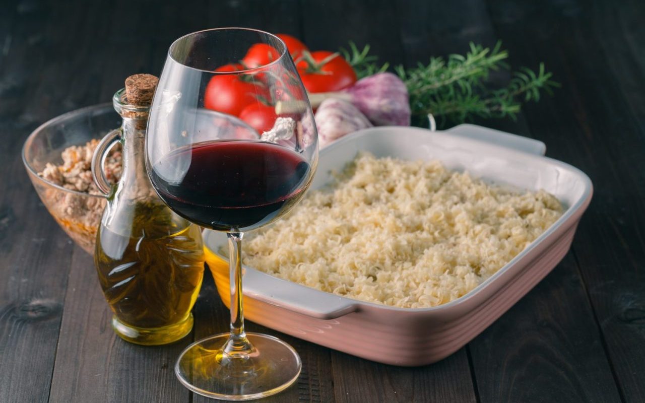 Plat de couscous aux légumes et à la viande servi avec une bouteille de vin rouge.